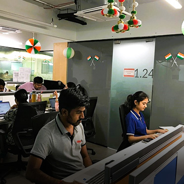 A group of people work on laptops in an office.