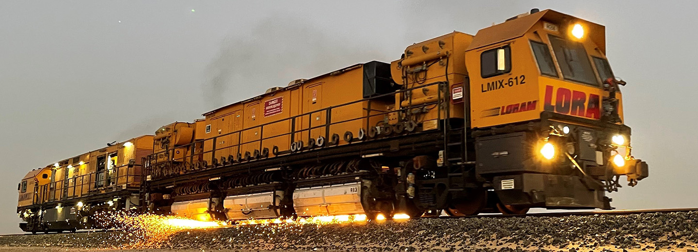 A yellow train on tracks causes sparks.